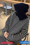 Person wearing a black and white striped sweater sitting in a chair.