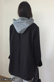 Person wearing a black coat with a striped hood against a white background