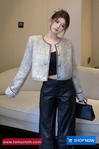 Woman wearing a light gray textured jacket over a black top and pants, holding a black handbag.