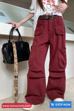 Person wearing red cargo pants holding a black handbag with a gold chain.