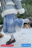 Person wearing a blue plaid coat with white fur trim in a snowy outdoor setting.