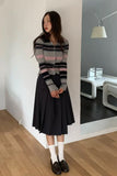 Woman wearing a striped sweater and black skirt in a modern room.