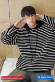 Person wearing a black and white striped hoodie with a neutral background